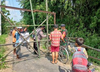 Jembatan Antar Desa Rusak, Anggota Bhabinkamtibmas Bantu Anak Sekolah Menyeberang