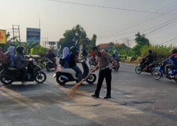 Mencegah Terjadinya Laka Lantas, Polisi Polres Mojokerto Kota  Bersihkan Tumpahan Minyak di Jalan