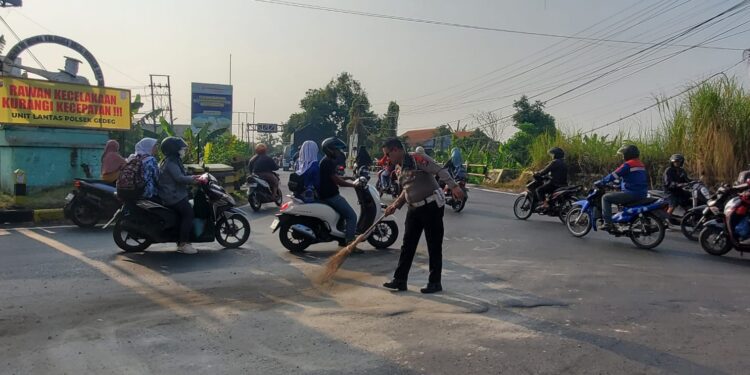 Mencegah Terjadinya Laka Lantas, Polisi Polres Mojokerto Kota  Bersihkan Tumpahan Minyak di Jalan